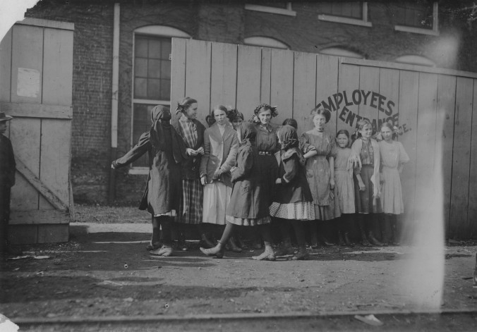 Photo of female mill workers standing outside the mill fence